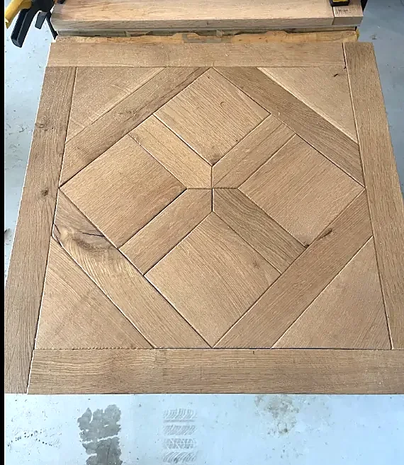 A square oak parquet panel with a diamond in a star pattern inside a mitered frame