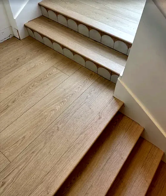 Light oak stair treads with scalloped white tile on the risers, turning at a landing